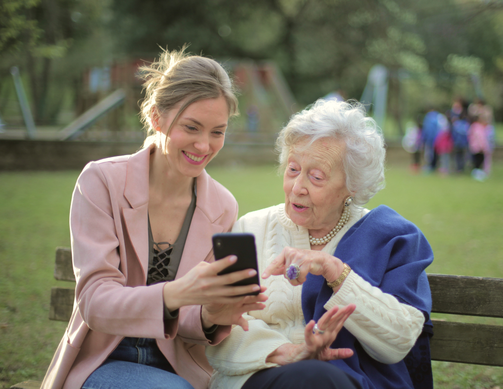 Young woman showing a senior woman how to use an iPhone.