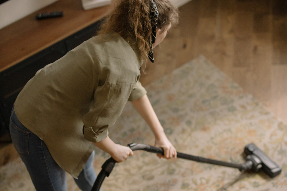 Young woman vacuuming the living room carpet.